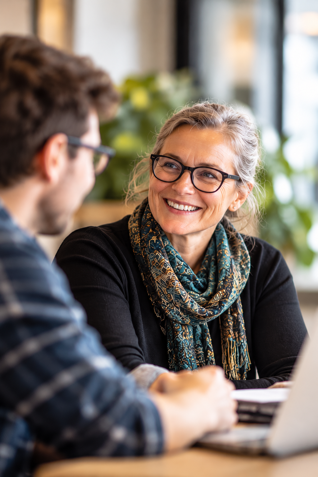 A smiling practitioner in conversation with a colleague across a table